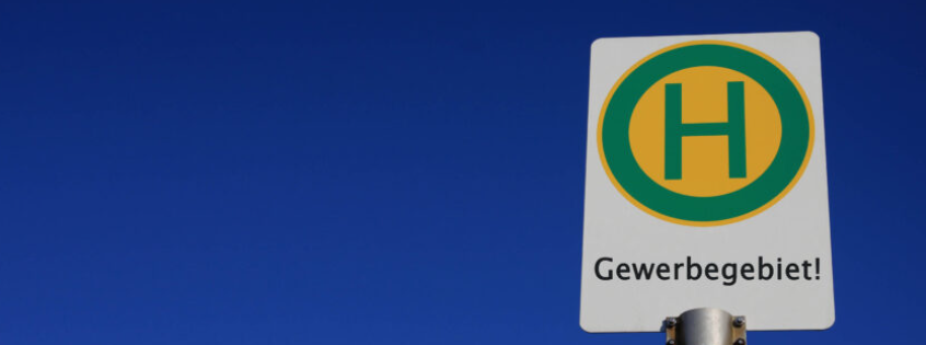 Auf dem Bild ist ein Haltestellenschild mit der Aufschrift Gewerbegebiet zu sehen